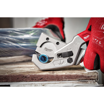 Rörskärare av märket Milwaukee, hålls av någon i röda handskar.