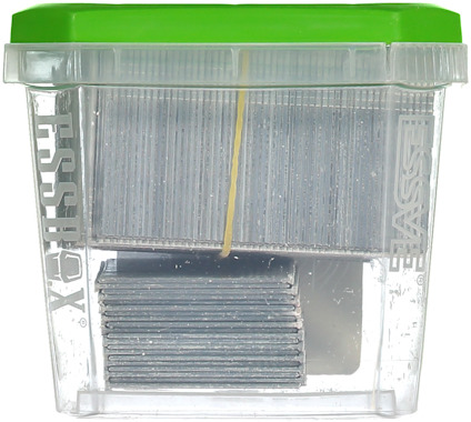 Plastlåda med grön lock innehållande grå spikar, märkt med texten "ESSVE".